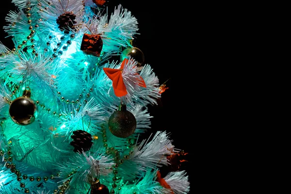 Süslü Noel ağacı. Karanlık bir arka planda Noel ağacı. Bir logo için boş yer. Renkli çelenk. Çok renkli ampuller. Karda beyaz Noel ağacı.