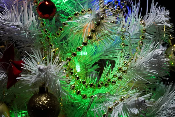 Süslü Noel ağacı. Karanlık bir arka planda Noel ağacı. Bir logo için boş yer. Renkli çelenk. Çok renkli ampuller. Karda beyaz Noel ağacı.