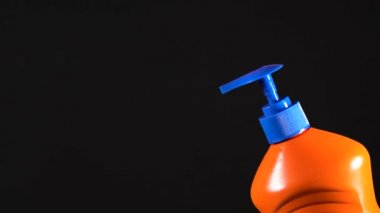 Turuncu deterjan şişesi. Etiketsiz ve isimsiz bir şişe. Elin deterjanı sıkıyor. Bulaşık deterjanı. Ev temizliği.