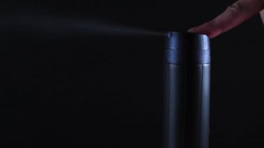Erkek eli deodorant püskürtür. İsimsiz ve logolu parfüm. Siyah bir arkaplanda.