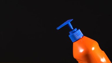 Turuncu deterjan şişesi. Etiketsiz ve isimsiz bir şişe. Elin deterjanı sıkıyor. Bulaşık deterjanı. Ev temizliği.