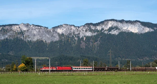 Komercyjne czerwony pociąg jedzie do austriackich Alpach. — Zdjęcie stockowe