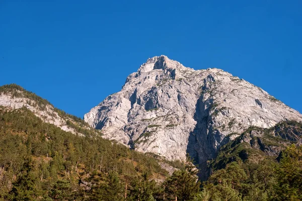 Corte de montanha nos Alpes Austríacos. As montanhas brancas são cercadas por outros, cobertas de árvores . — Fotografia de Stock