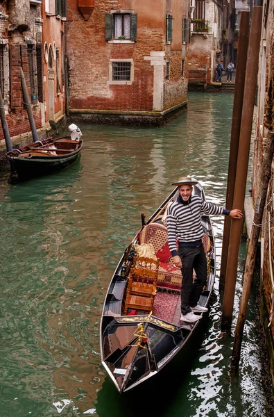 Венеція, Італія - 13 жовтня 2017: Gondolier зупинився в очікуванні пасажирів. Gondolier смугастий пуловер і солом'яний капелюшок. Гондоли багато прикрашені червоними килимами. — стокове фото