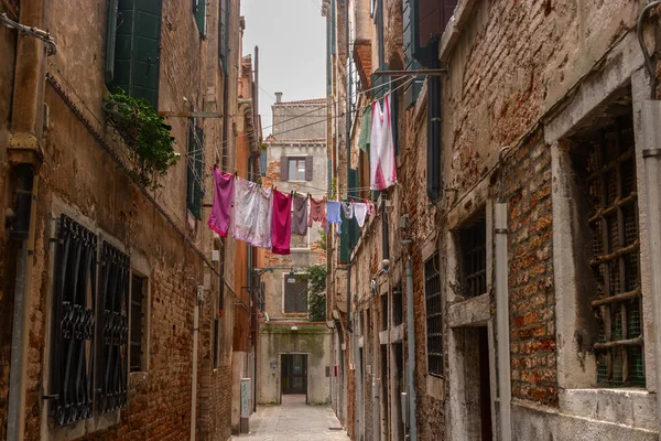 Calle estrecha en Venecia. Por encima de la calle en el tendedero colgado ropa colgada lavada . — Foto de Stock