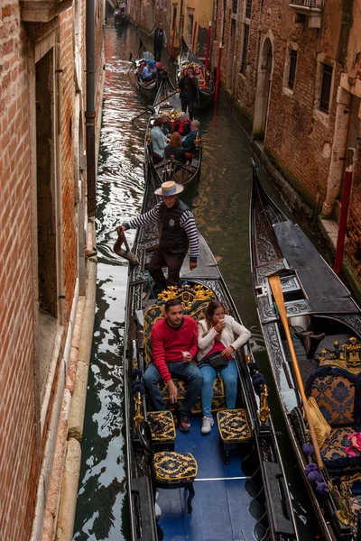 Venezia, 13 ottobre 2017: I turisti navigano su una gondola su uno stretto canale. La gondola è riccamente decorata con tappeti rossi e ornamenti in oro . — Foto Stock