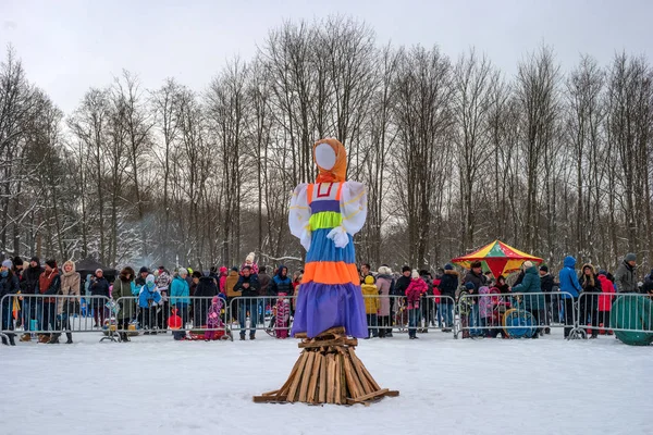 Гатчина, Россия - 18 февраля 2018 года: Масленичный праздник. Масленица. Большая кукла готова к сжиганию. Зрители стоят за забором и радуются . — стоковое фото