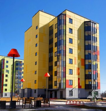 Gatchina, Rusya - 7 Nisan 2018: Modern yeni binalar mavi gökyüzü. Binalar parlak sarı ve yeşil renklendirme var. Bahçeye portakal Abajur ile sokak ışıkları vardır.