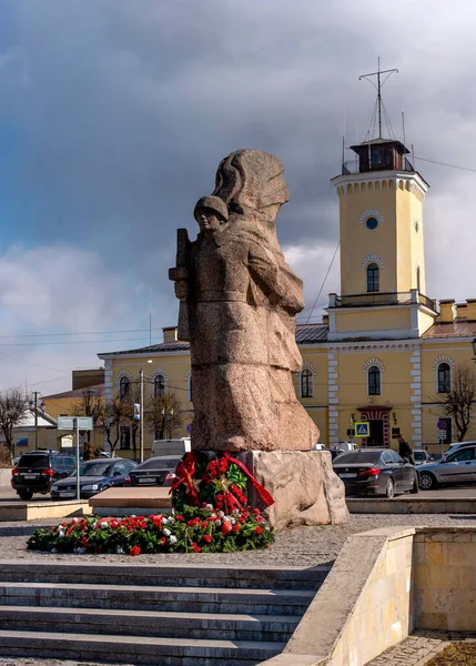 Gatchina, Rússia - 30 de março de 2020: Memorial da Grande Guerra Patriótica. Monumento a soldados caídos. De um soldado esculpido em granito com uma arma. No fundo é um antigo quartel de bombeiros — Fotografia de Stock