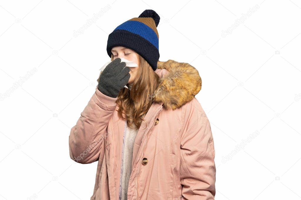 young woman in winter clothes is holding a handkerchief and blow one's nose