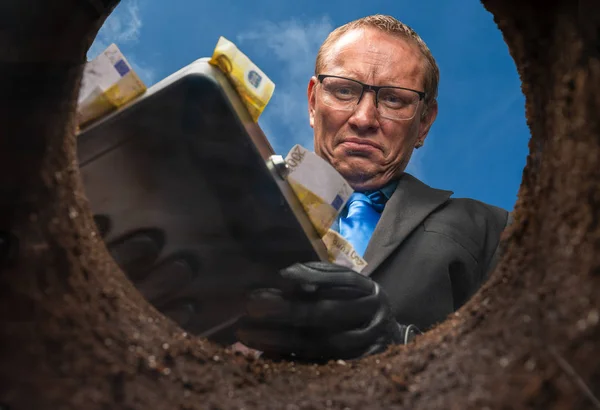 Egy üzletember elássa a pénzét egy földbe. — Stock Fotó