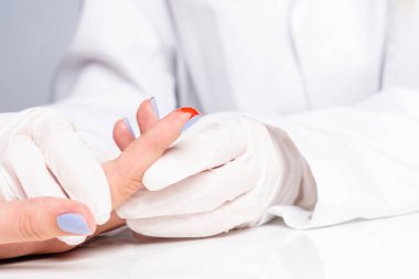 Bir doktor elindeki kesik yarasını muayene eder.