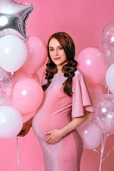 Mulher grávida feliz em vestido de noite rosa em pé no confete — Fotografia de Stock