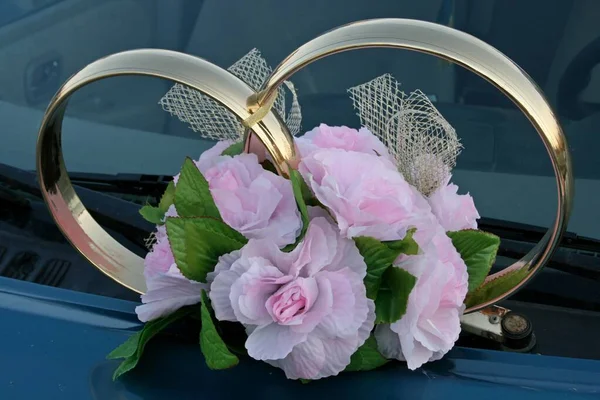 Anillos de boda decorativos y flores artificiales montadas en un coche — Foto de Stock