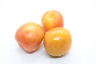 Beyaz arkaplanda portakallı ıslak lezzetli erikler var.