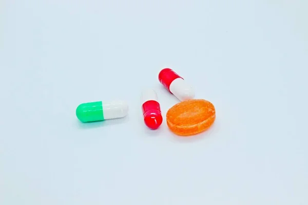 Pílulas multi-coloridas estão localizados em um fundo branco — Fotografia de Stock