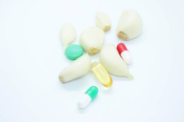 Beyaz arka planda bulunan sarımsak karanfilleri ve tabletler