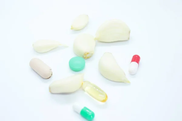 Stroužky česneku a tablety umístěné na bílém pozadí — Stock fotografie
