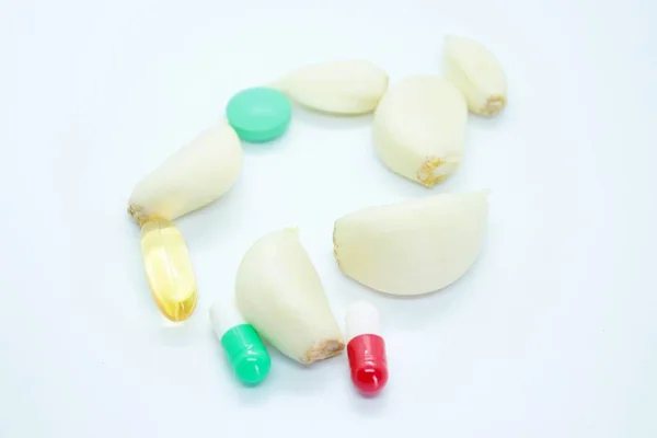 Garlic cloves and tablets located on a white background — Stock Photo, Image