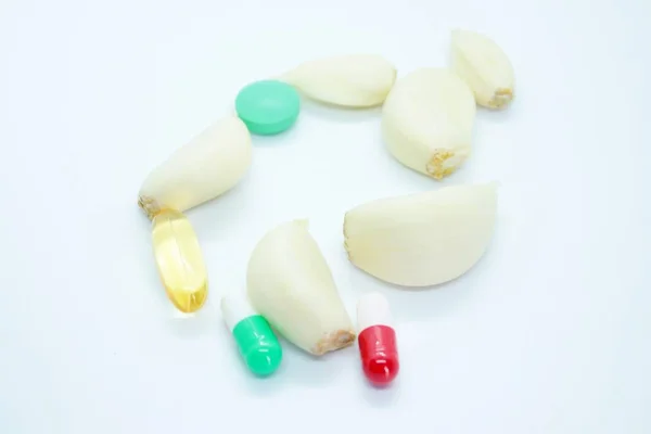 Garlic cloves and tablets located on a white background — Stock Photo, Image