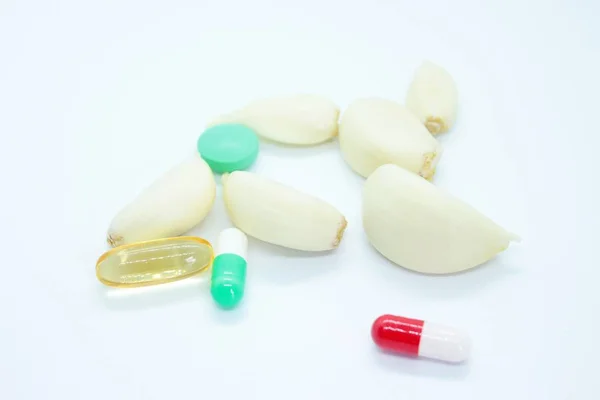 Knoflookteentjes en -tabletten op een witte achtergrond — Stockfoto