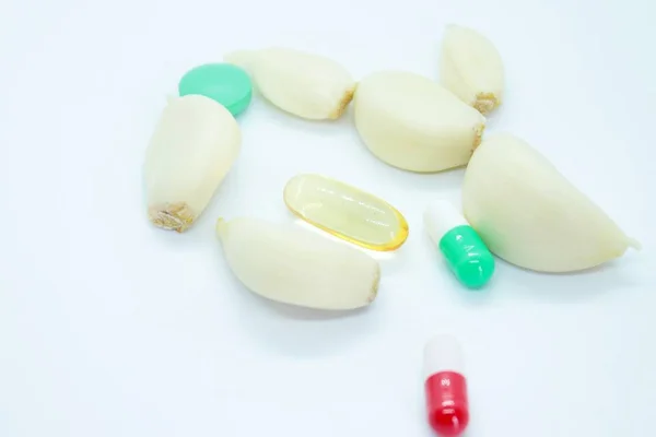 Knoblauchzehen und Tabletten auf weißem Hintergrund — Stockfoto