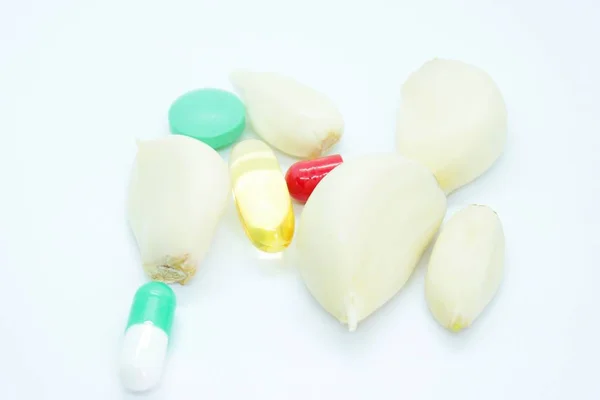 Stroužky česneku a tablety umístěné na bílém pozadí — Stock fotografie