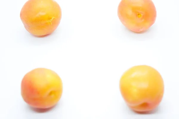 Ciruelas anaranjadas maduras posadas sobre un fondo blanco — Foto de Stock