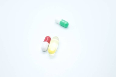 Tabletler, kapsüller, vitaminler, beyaz arka planda yer almaktadır.