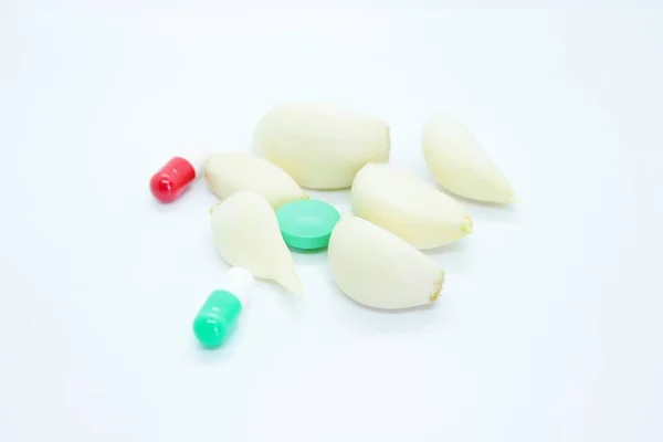 Česnek a vitamíny se nacházejí na bílém pozadí — Stock fotografie