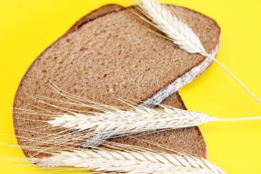 Çavdar ekmeği ve çavdar kulakları sarı arka planda yer alır.