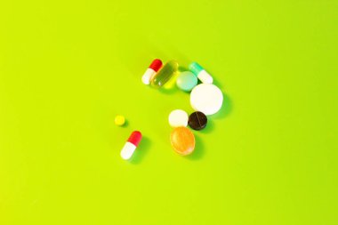 Yeşil arka planda bulunan haplar vitamin ilaçları.