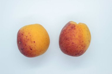 Beyaz arka planda olgun, güzel kayısılar bulunur.