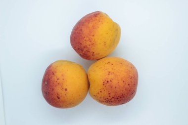 Beyaz arka planda olgun, güzel kayısılar bulunur.