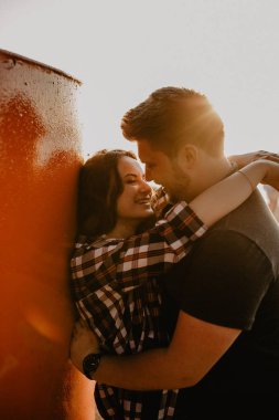 Güzel mutlu çift göl kenarında eğleniyor. Gün batımında romantik bir fotoğraf. Sarılmak ve gülümsemek.