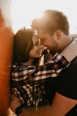 Güzel mutlu çift göl kenarında eğleniyor. Gün batımında romantik bir fotoğraf. Sarılmak ve gülümsemek.