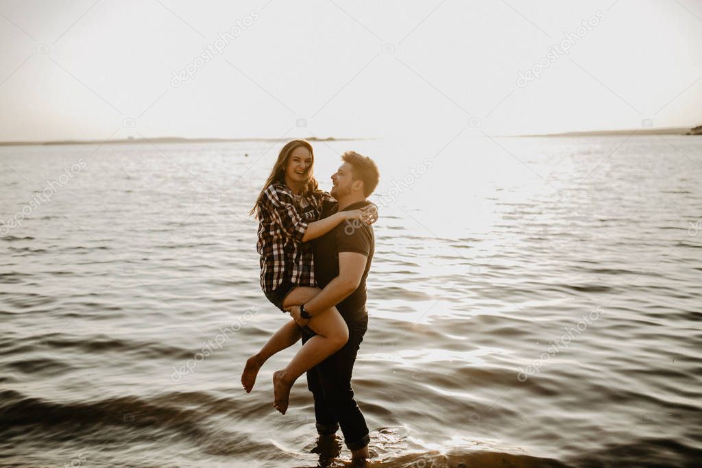 Lovely happy couple having fun near the lake. romantic photo at sunset time. Hugging  and smiling