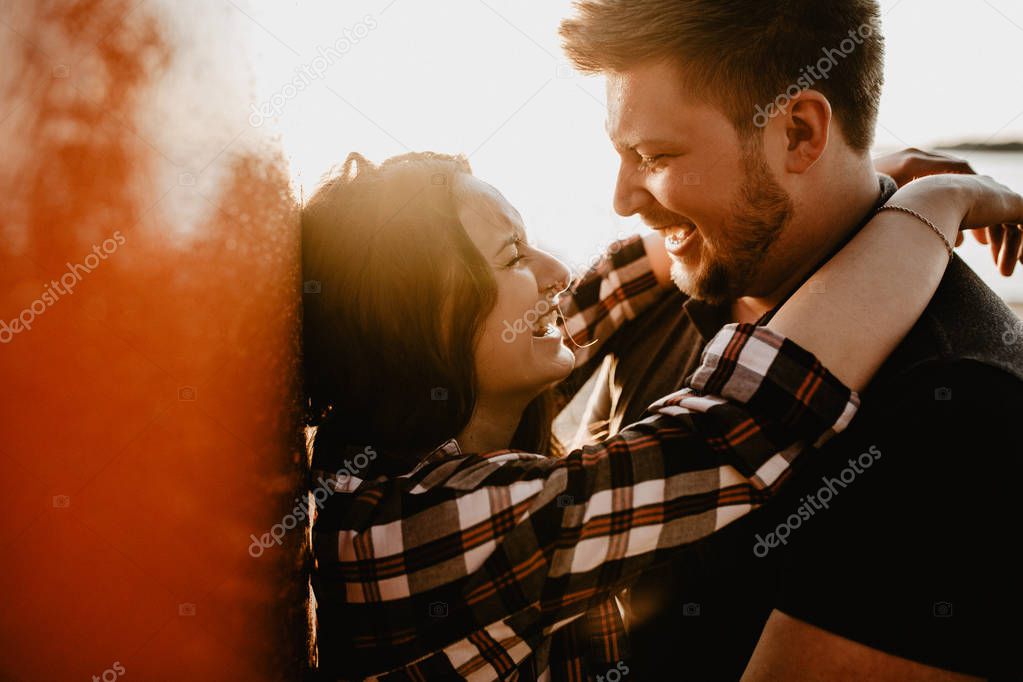 Lovely happy couple having fun near the lake. romantic photo at sunset time. Hugging  and smiling
