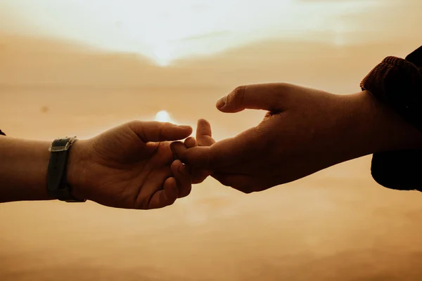 Gün batımında yürürken el ele tutuşan sevgili çiftin yakın çekimi.