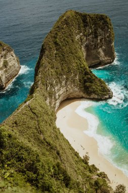 Uçurumun eteğindeki vahşi tropik plaj. Kayalık kayalıkların arasında tropik bir sahil. Endonezya, Bali 'deki Nusa Penida Adası' ndaki Manta Körfezi veya Kelingking Sahili. Seyahat konsepti. Bali 'de seyahat hedefi.