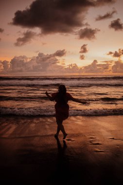 Gün batımında mutlu koşan kız silueti. Renkli günbatımının tadını çıkar.