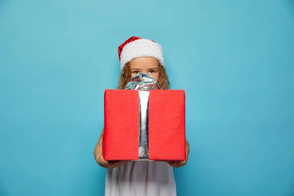 Noel Baba 'nın kırmızı şapkalı kızı Noel hediyesi taşıyor. — Stok fotoğraf