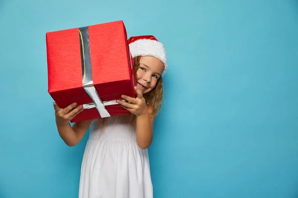 Flicka i Santa röd hatt håller julklapp — Stockfoto