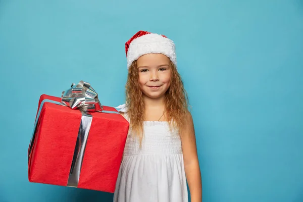 Mädchen mit Weihnachtsmann roten Hut hält Weihnachtsgeschenk — Stockfoto