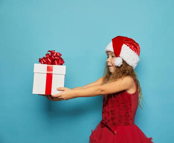 Noel Baba 'nın kırmızı şapkalı kızı Noel hediyesi taşıyor. — Stok fotoğraf