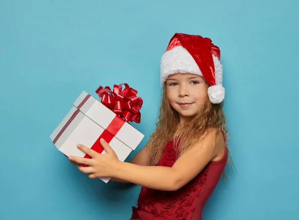 Mädchen mit Weihnachtsmann roten Hut hält Weihnachtsgeschenk — Stockfoto