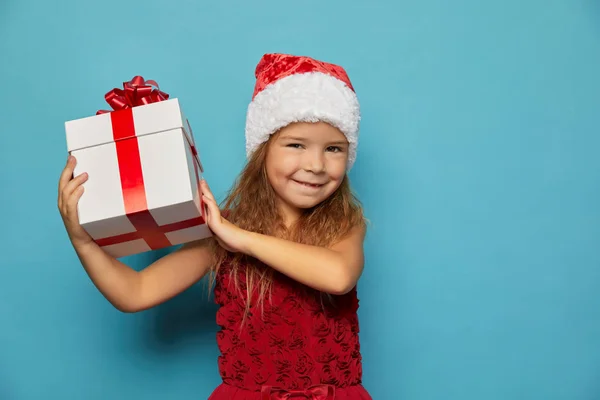 Menina em Santa chapéu vermelho segurando presente de Natal — Fotografia de Stock
