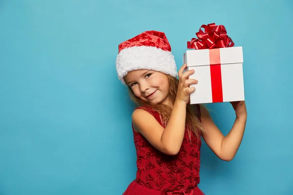 Girl in Santa red hat holding Christmas gift — Stock Photo, Image