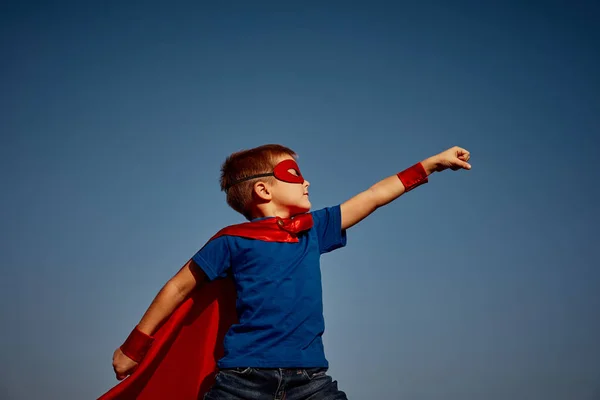 Criança super-herói (menino) contra o céu azul — Fotografia de Stock