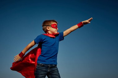 Süper kahraman çocuk mavi gökyüzüne karşı